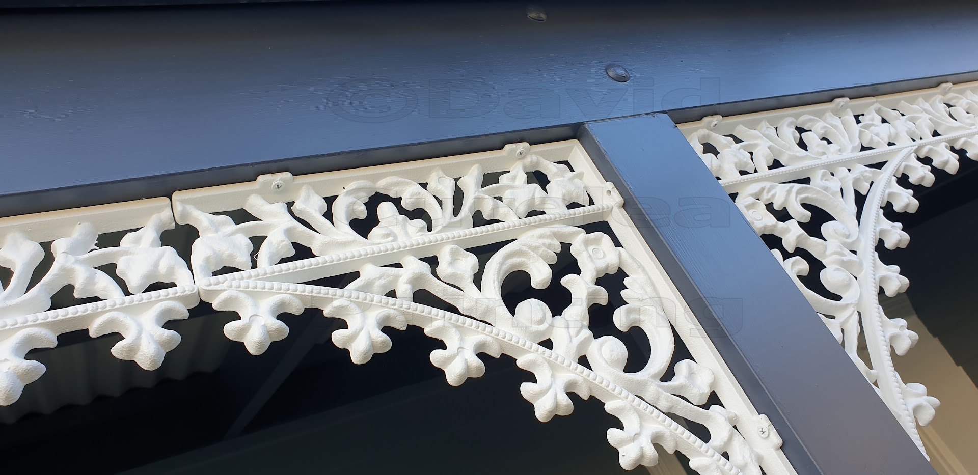 White cast-iron verandah lacework against a navy beam