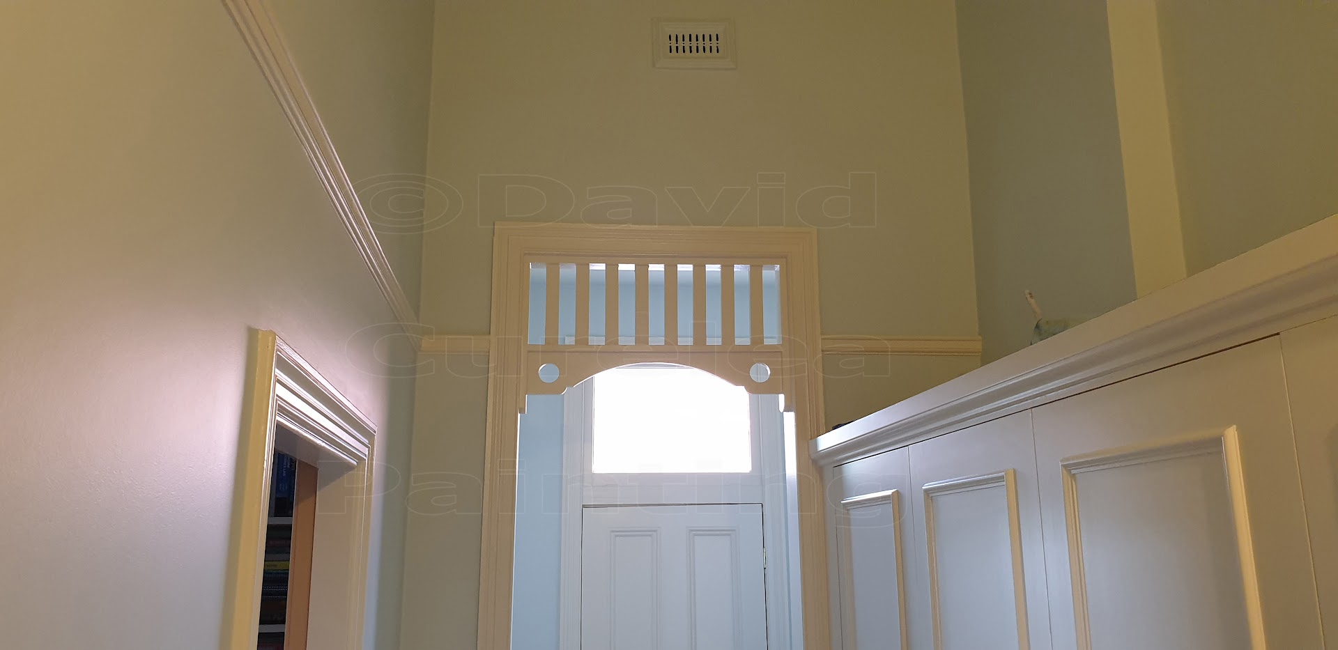 An interior hallway with painted wall panelling and a door