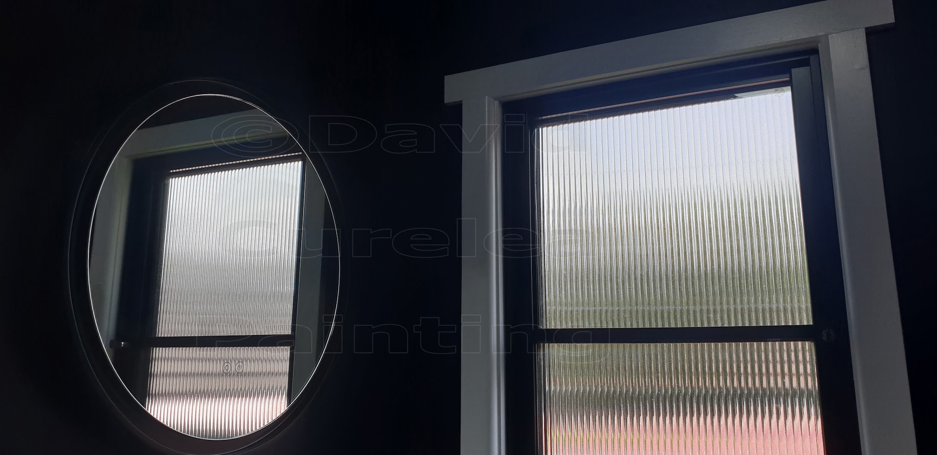 Window frames painted dark navy beside a round mirror