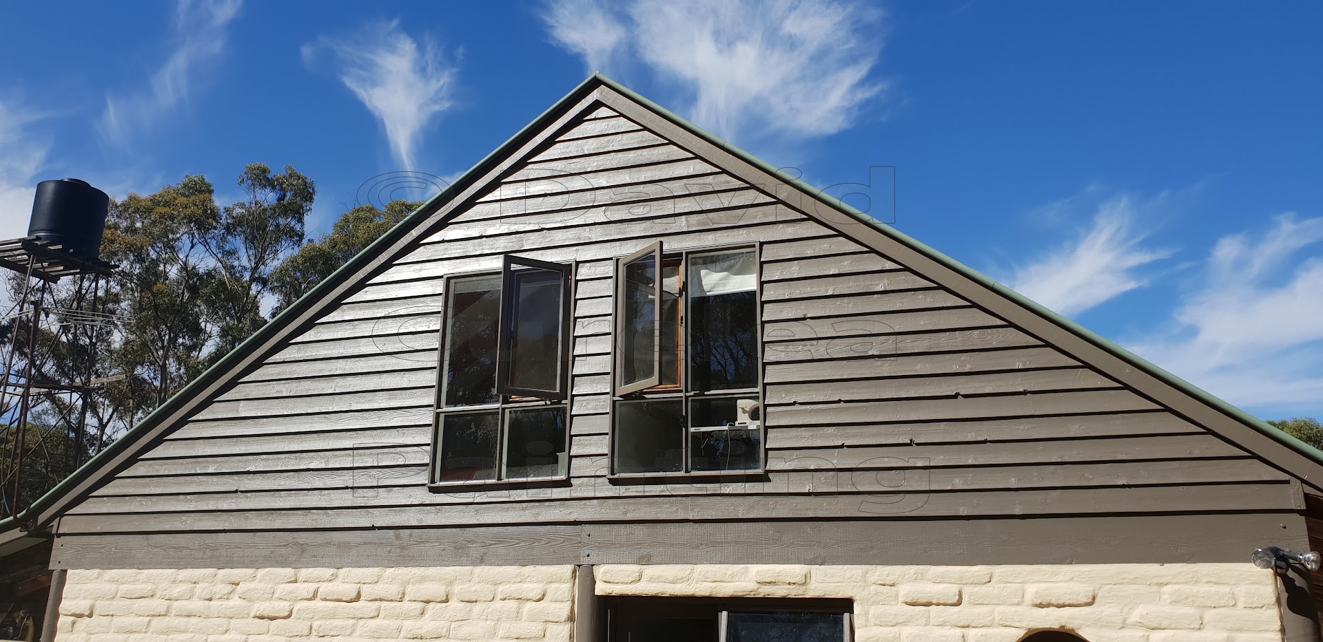 A painted gable end and window frames against a clear sky