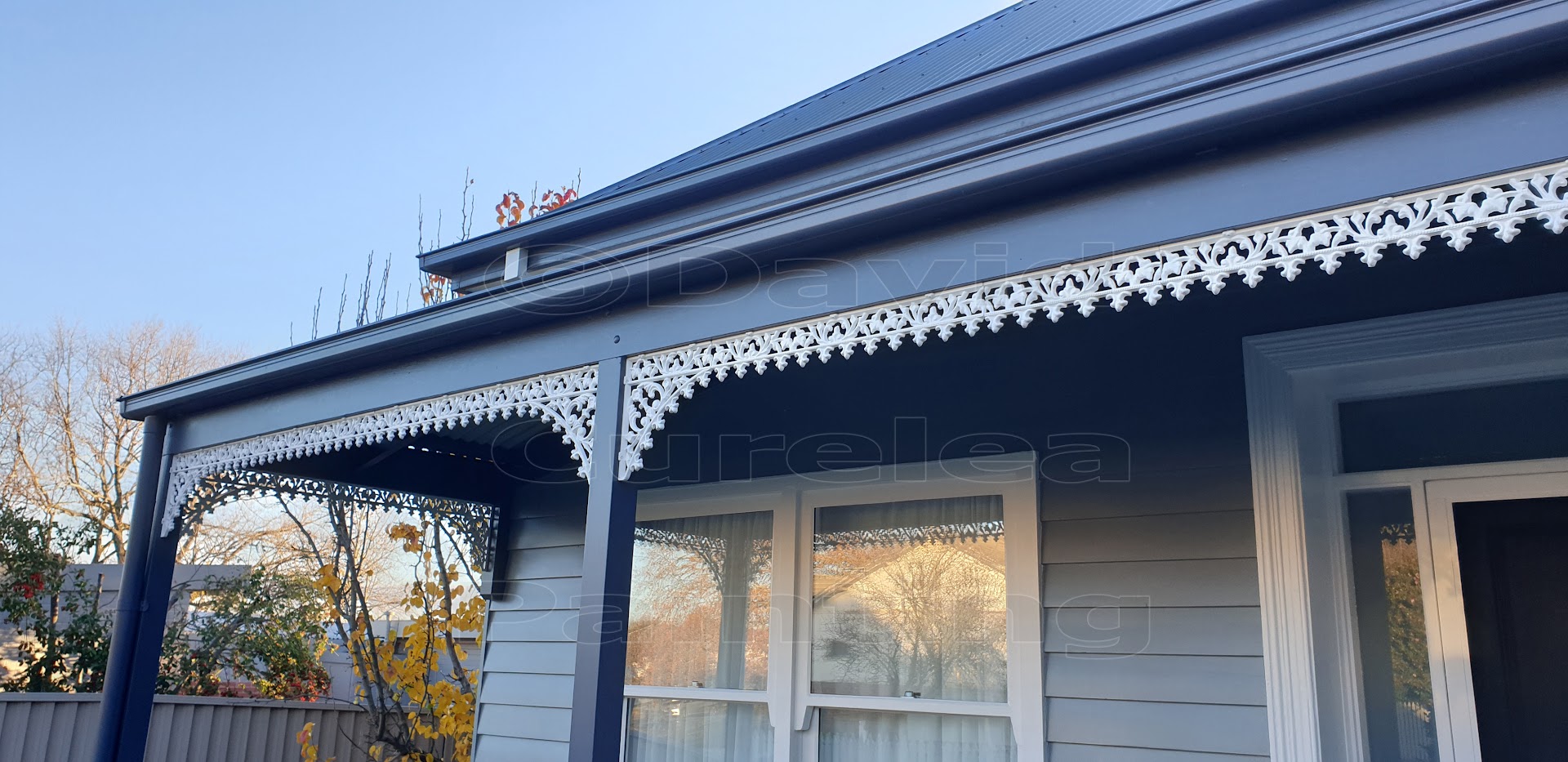 A verandah with navy beams and white cast-iron lacework on a Ballarat home