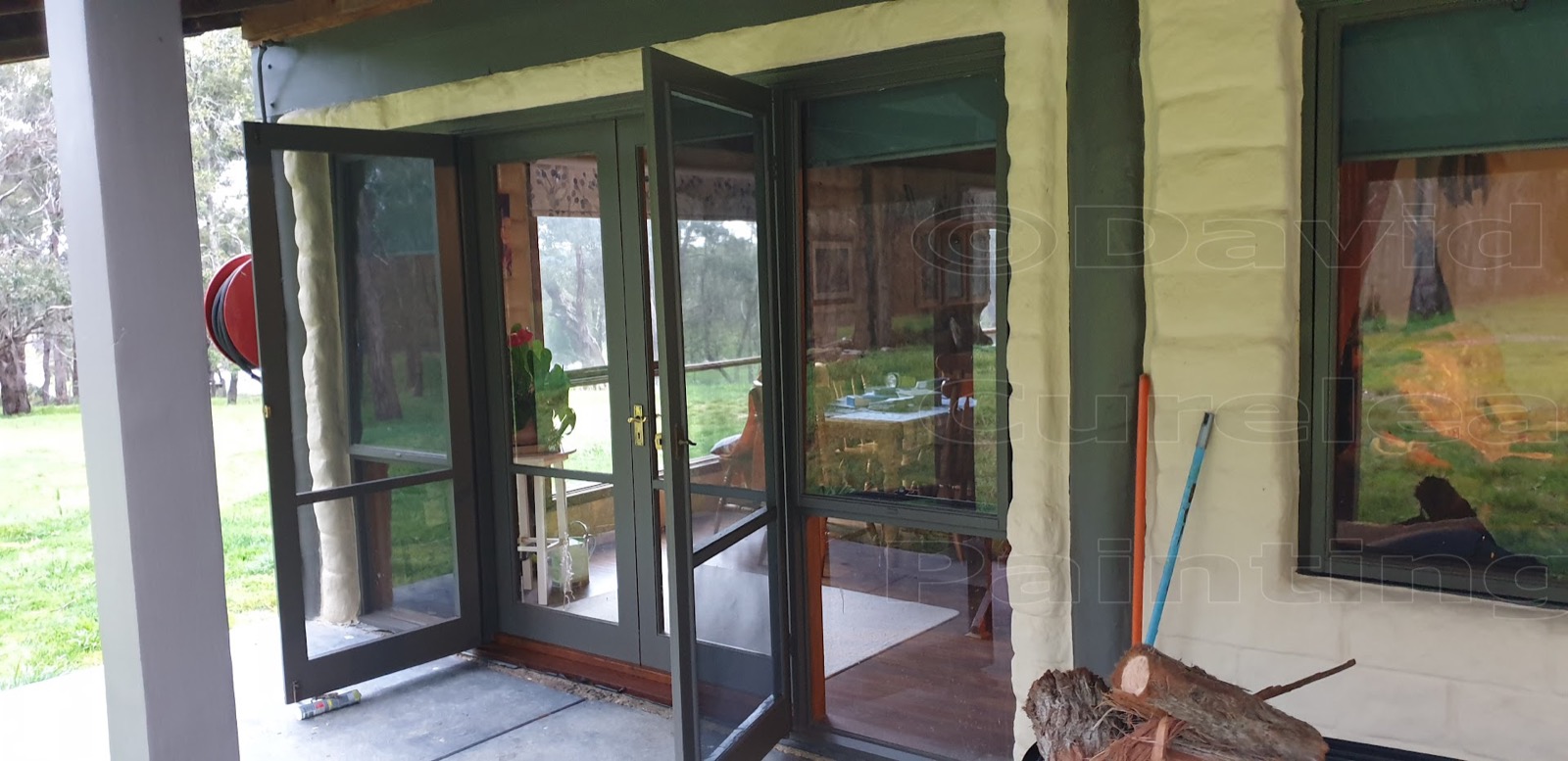 Open timber windows painted green, with work in progress