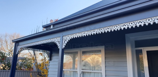 A verandah with navy beams and white cast-iron lacework
