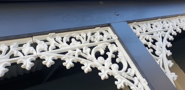 White cast-iron verandah lacework against a navy beam