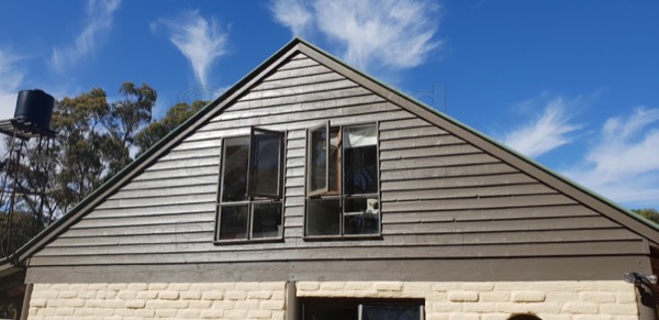 A painted gable end and window frames against a clear sky