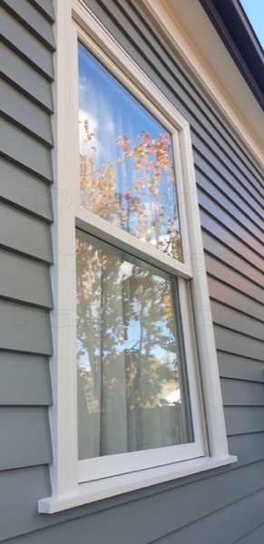 A double-hung window with painted frames on grey weatherboard
