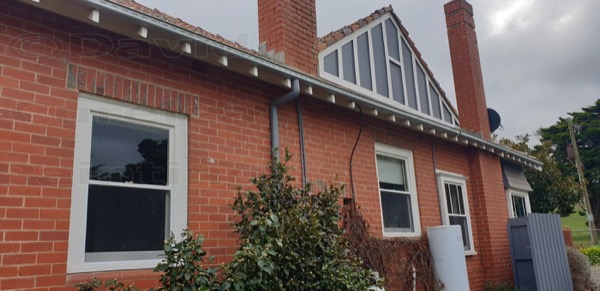 A red brick home with painted window frames and gable