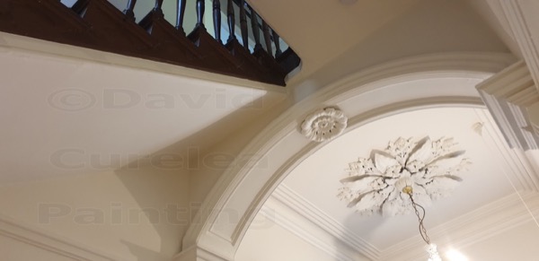 An arched hallway opening with a plaster ceiling rose