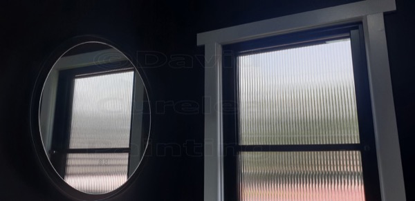 Window frames painted dark navy beside a round mirror