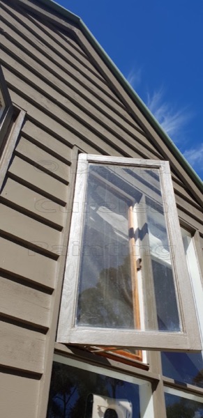 A weatherboard wall and painted window seen from below