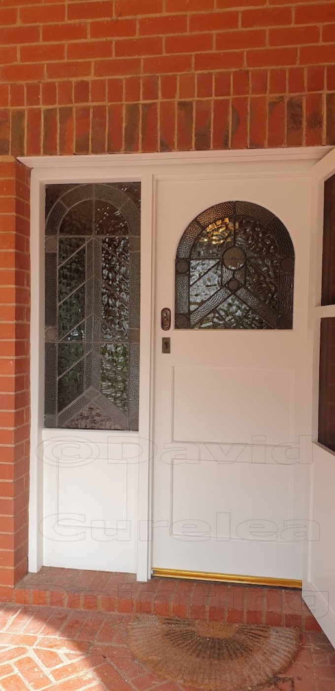 A painted front door and side panel on a brick porch