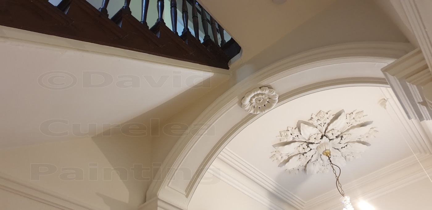 An arched hallway opening with a plaster ceiling rose